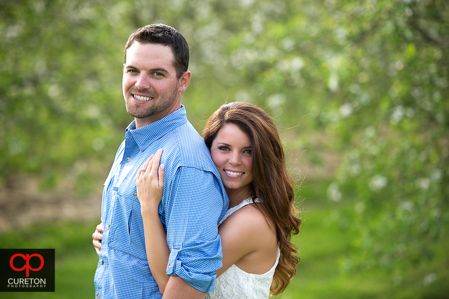 Bride and Groom to be standing in an apple orchard.