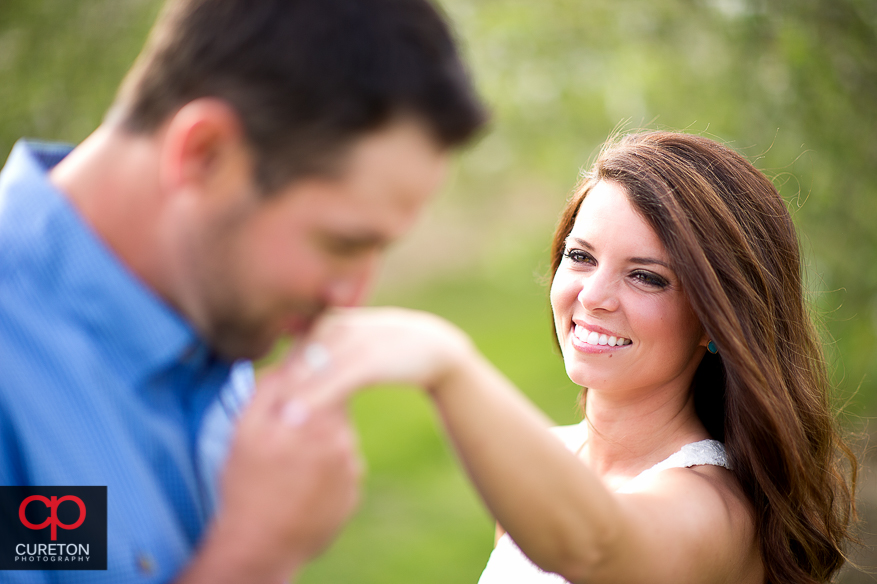 Groom kissing his bride to be's ring during their recent engagement session at an apple orchard in Hendersonville,NC.