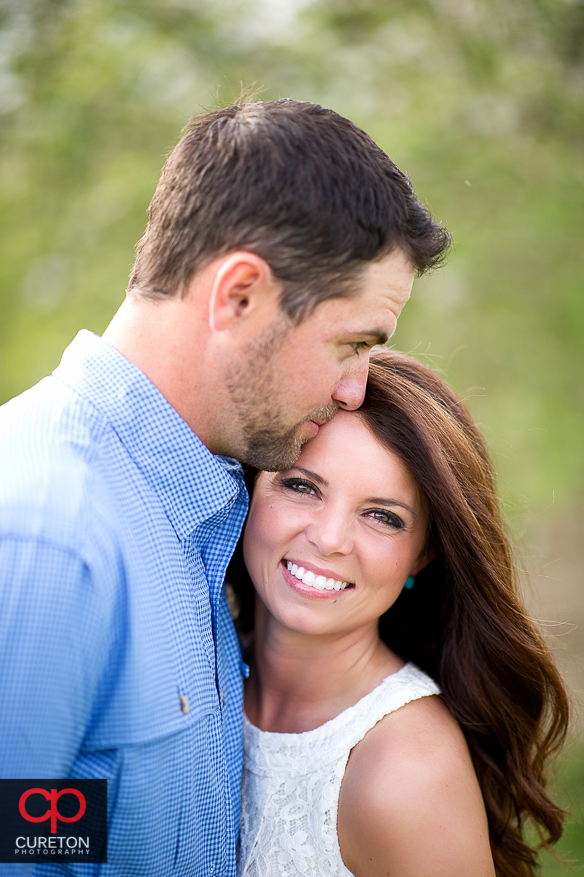 Man kissing his fiancee on the forehead.