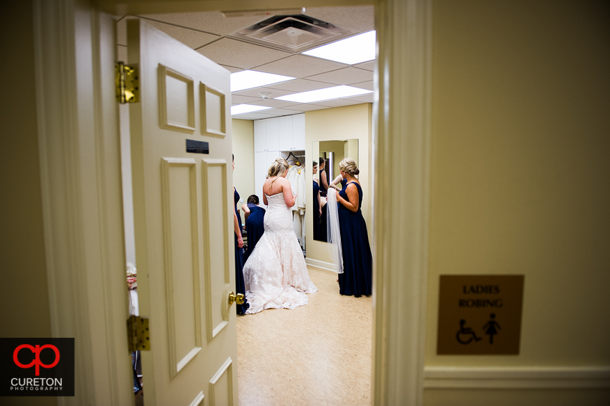 Bridesmiads help the bride into her dress.