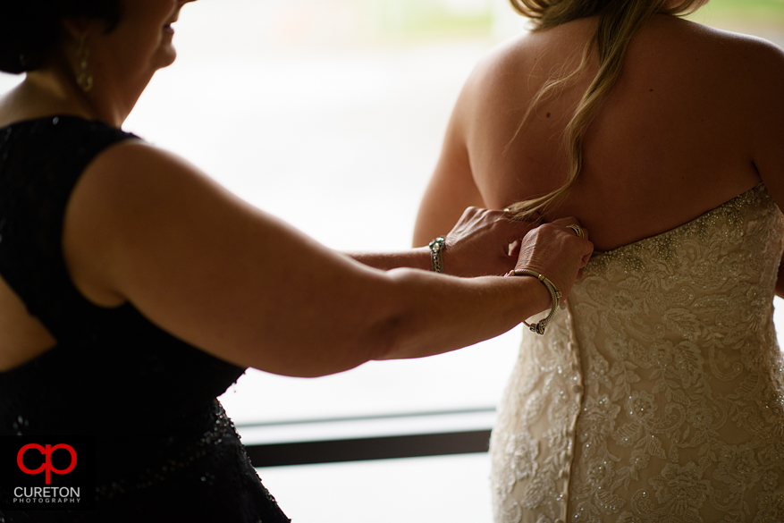 Bridesmiads help the bride into her dress.