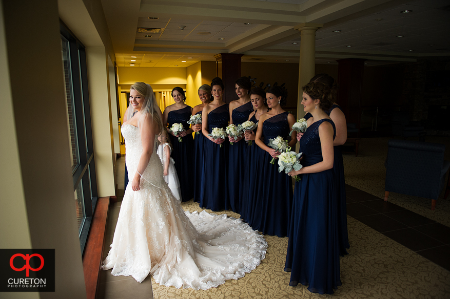 Bridesmiads help the bride into her dress.