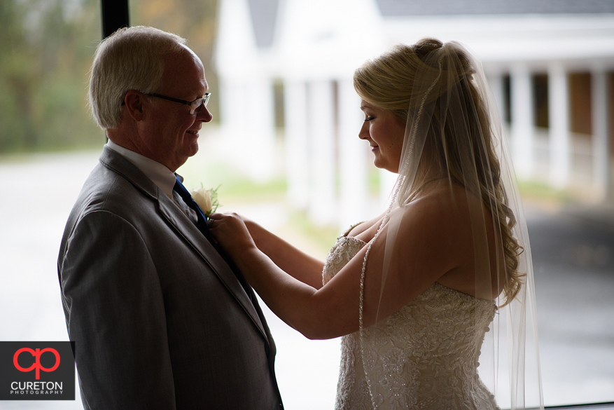 Bride helps her father pin flower.