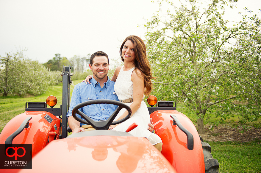 Couple sitting on a tractor during their recent engagement session at an apple orchard in Hendersonville,NC.