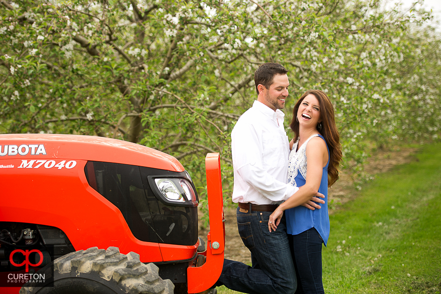 Bride to be laughing beside a tractor.