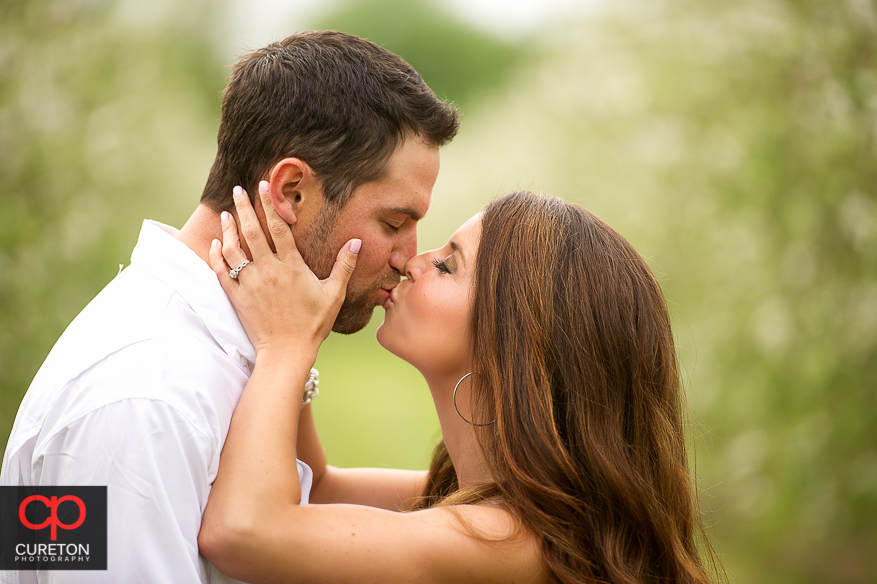 Girl kissing her fiancee during their recent engagement session at an apple orchard in Hendersonville,NC..