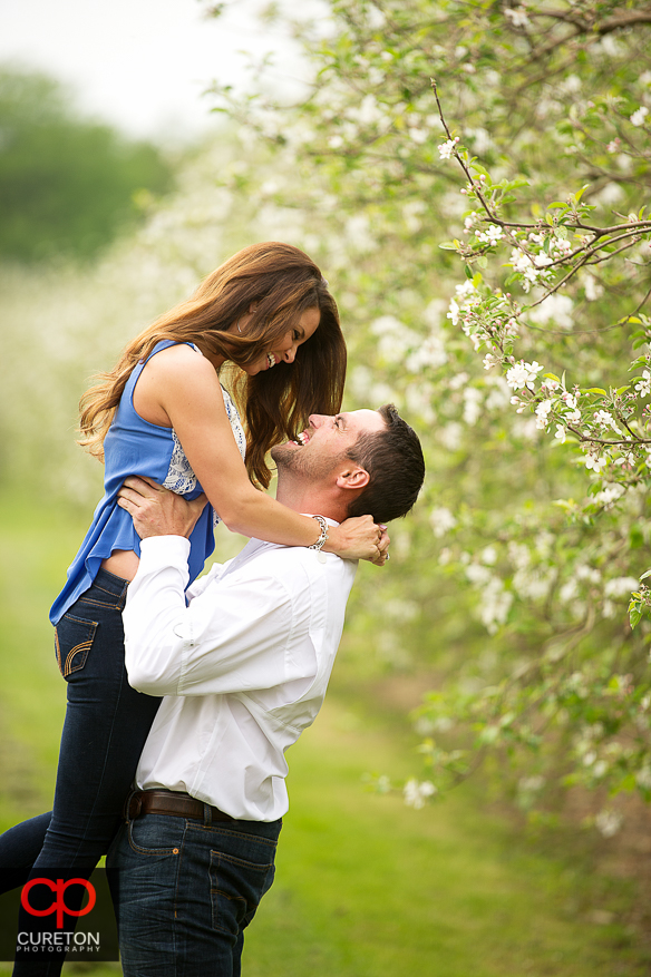 Groom lifting his bride to be in a n apple orchard.