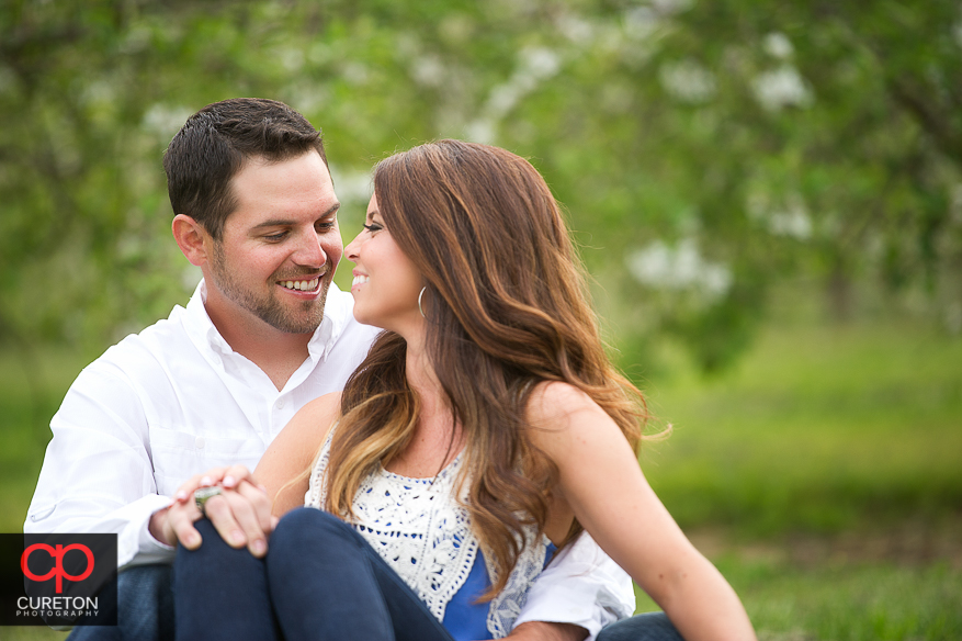 Couple sitting down in an apple orchard.