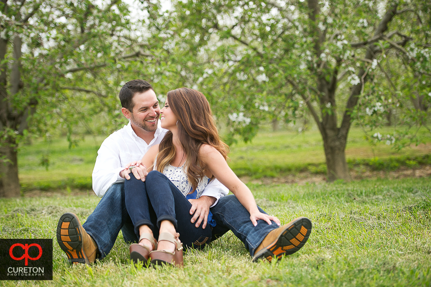 Couple sitting looking at each other during their recent engagement session at an apple orchard in Hendersonville,NC.