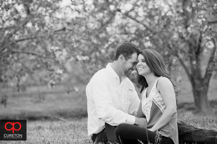 Bride and groom sitting next to each other in an apple orchard.