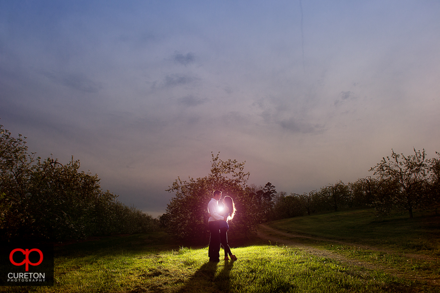 Couple kissing at sunset during their recent engagement session at an apple orchard in Hendersonville,NC.