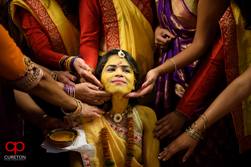 Indian bride gets the pithi put on her face before her wedding.