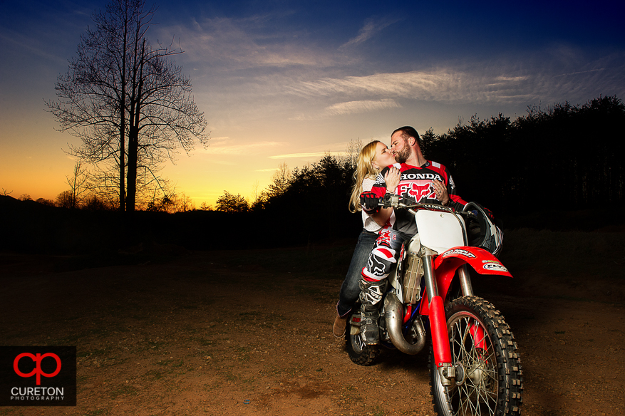 Couple on a motorcycle kissing at sunset.