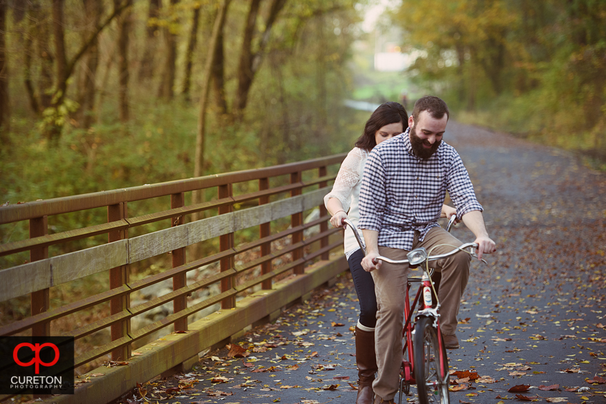 Engaged couple rising a tandem bicycle.