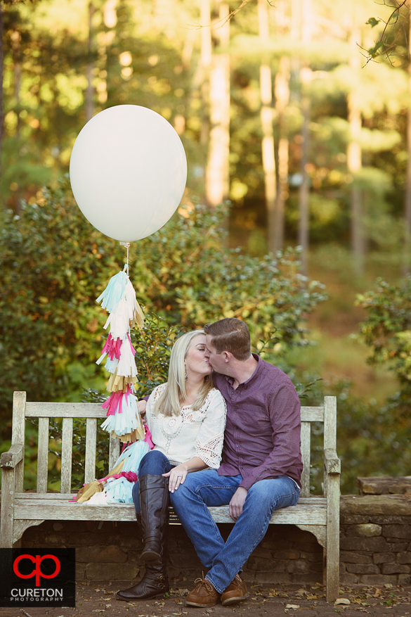 Couple with balloon kissing at a Botanical Garden engagement session in Clemson,SC..