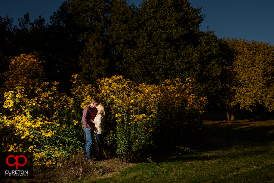 Engaged couple standing in flowers at a Botanical Garden engagement session in Clemson,SC..