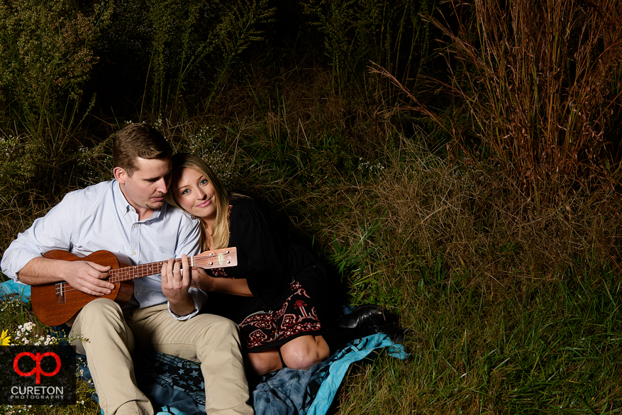 Engagement photo with a couple on a blanket playing guitar.