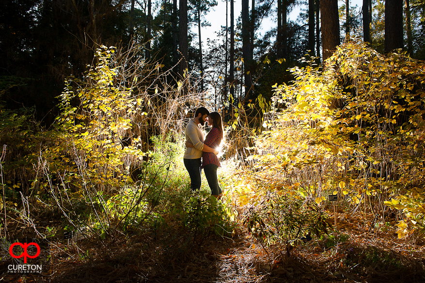 A couple in some bushes during their Botanical Gardens engagement session in Clemson,SC.