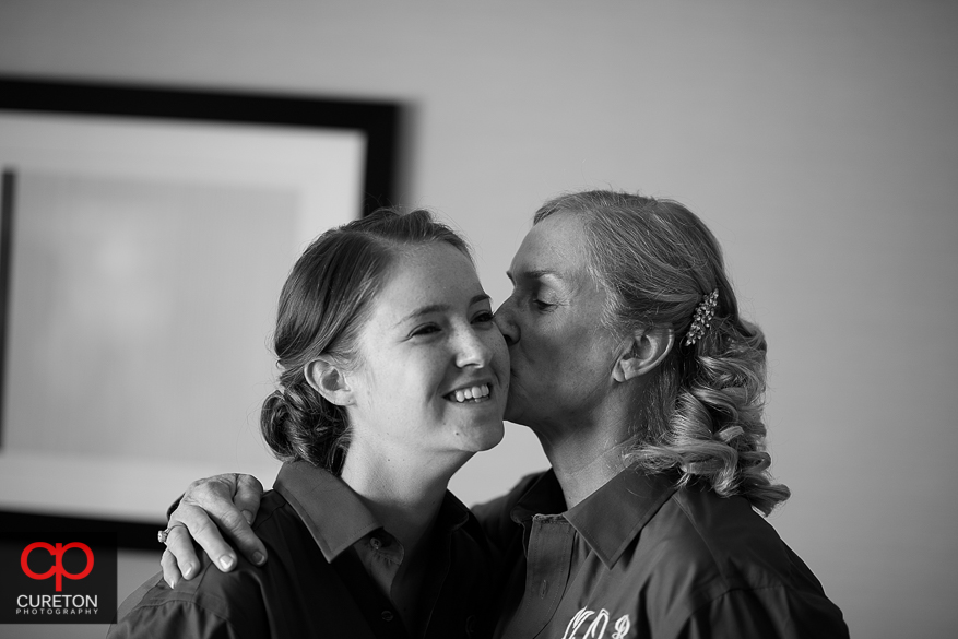 Brides mother kisses her on the cheek while she's getting ready before her wedding.