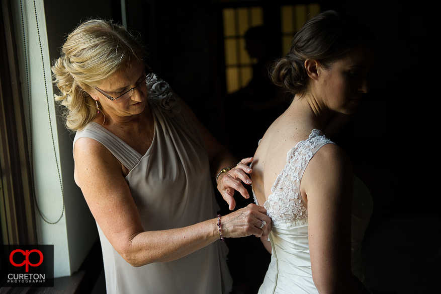 The bride's mother helps her into the dress.