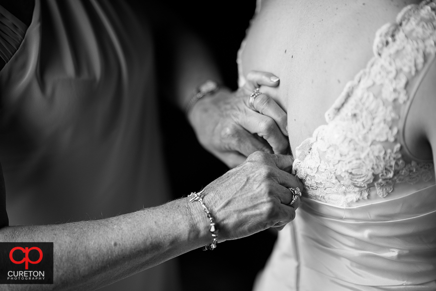 The brides mother's hands helping zip her dress.