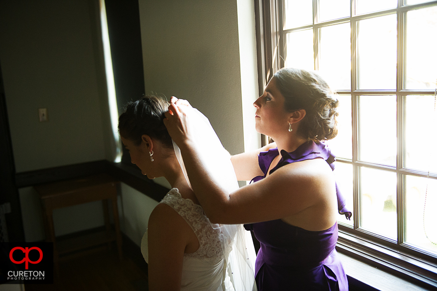 The bridesmaids helping the bride get int over dress.