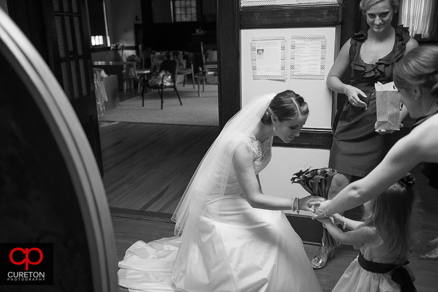 The flower girl hands the bride some flowers.