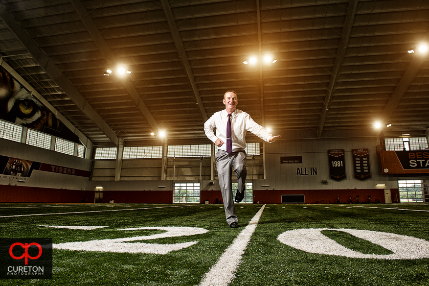 The groom doing hi heisman pose in the Clemson football indoor complex.