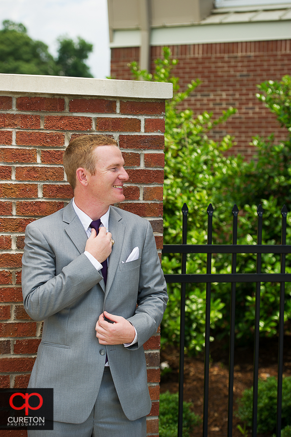 The groom adjusts his tie.