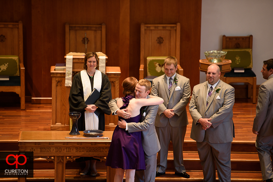 The groom hugs his sister during the processional.