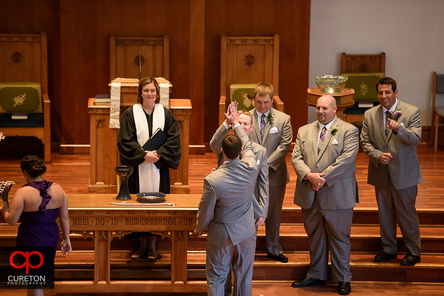 The groom and his groomsmen high-five.