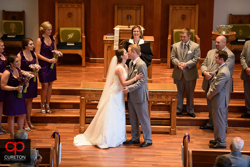 The bride and groom share a first kiss at their wedding.