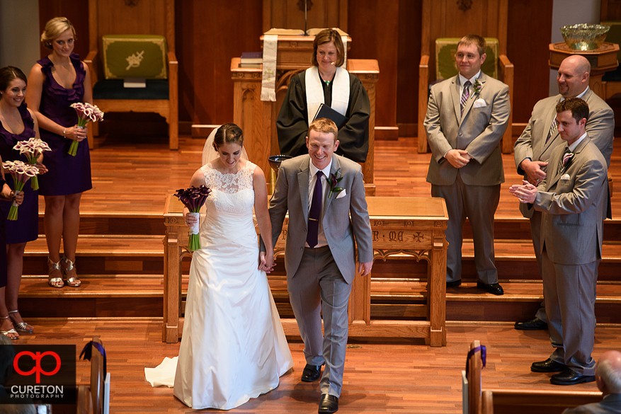 The bride and groom walk back down the aisle married.