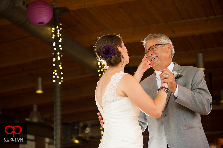 The bride wipes tears from her fathers eyes during their dance.