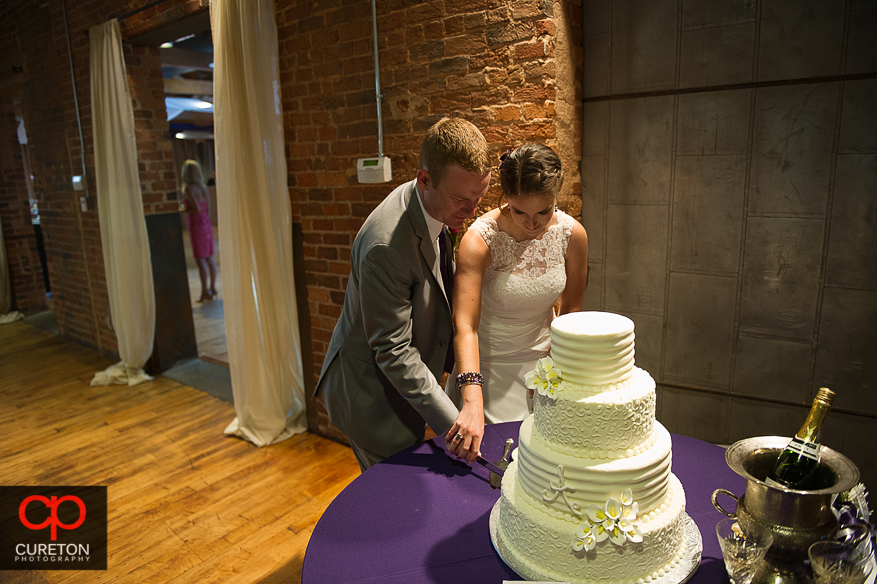 The bride and groom cutting a beautiful cake by Kathy and Company.