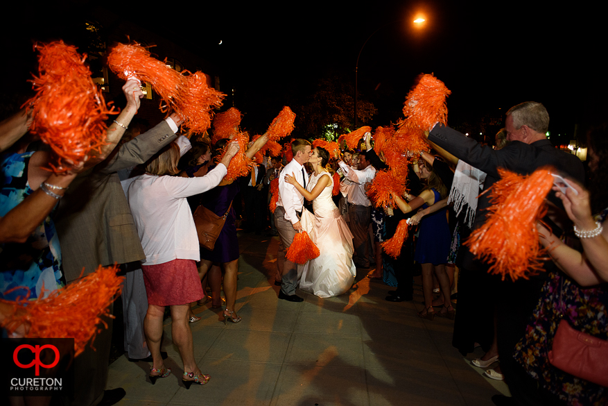 The bride and groom leave while the guests shake Clemson shakers.