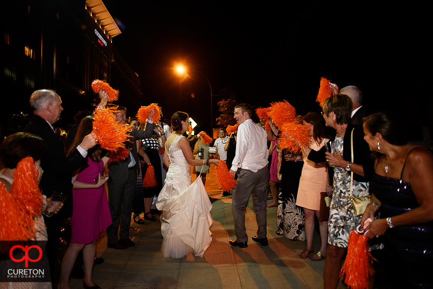 The bride and groom leave while the guests shake Clemson shakers.
