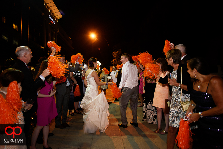 The bride and groom leave while the guests shake Clemson shakers.