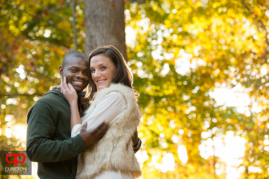 Engaged couple standing in front of an amazing fall color backdrop in downtown Greenville SC.