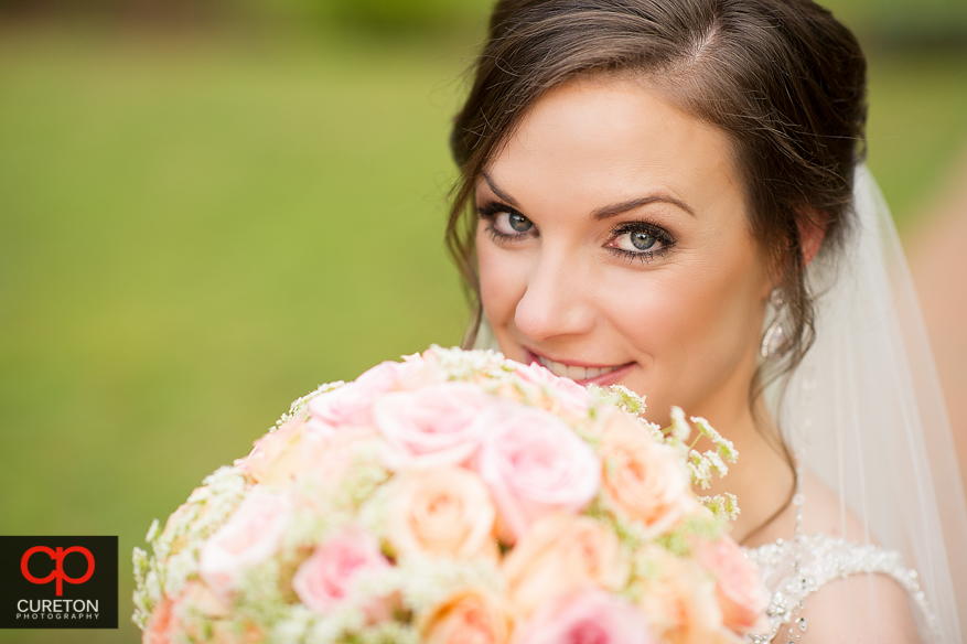 Bride smiling with her flowers in front of her at the Duncan Estate in Spartanburg,SC..