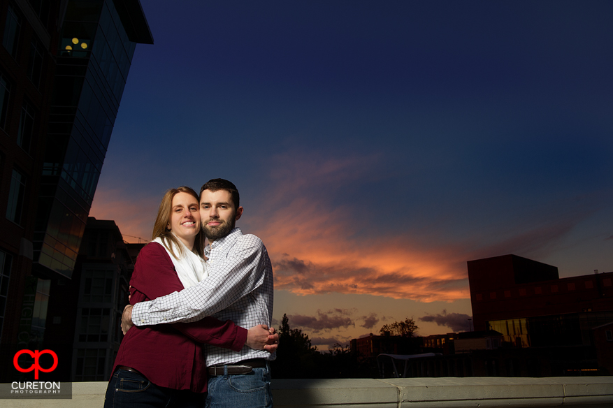 A couple hugging on the bridge in downtown Greenville during sunset.