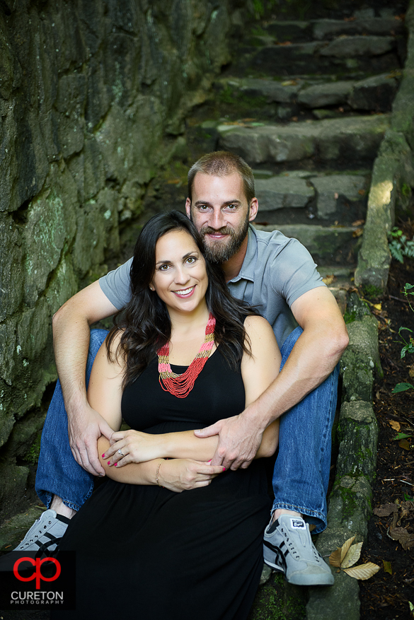 Engaged couple sitting on the steps in Falls Park.