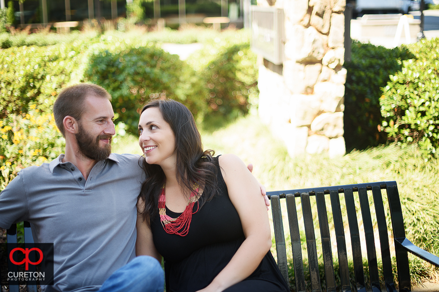 Engaged couple sitting on a bench.