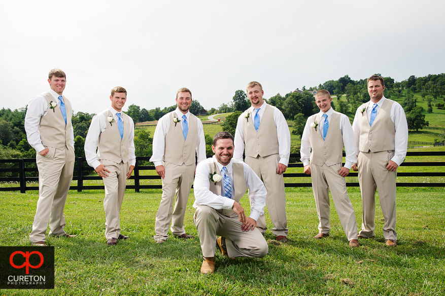 Groomsmen posing in front of a fence.