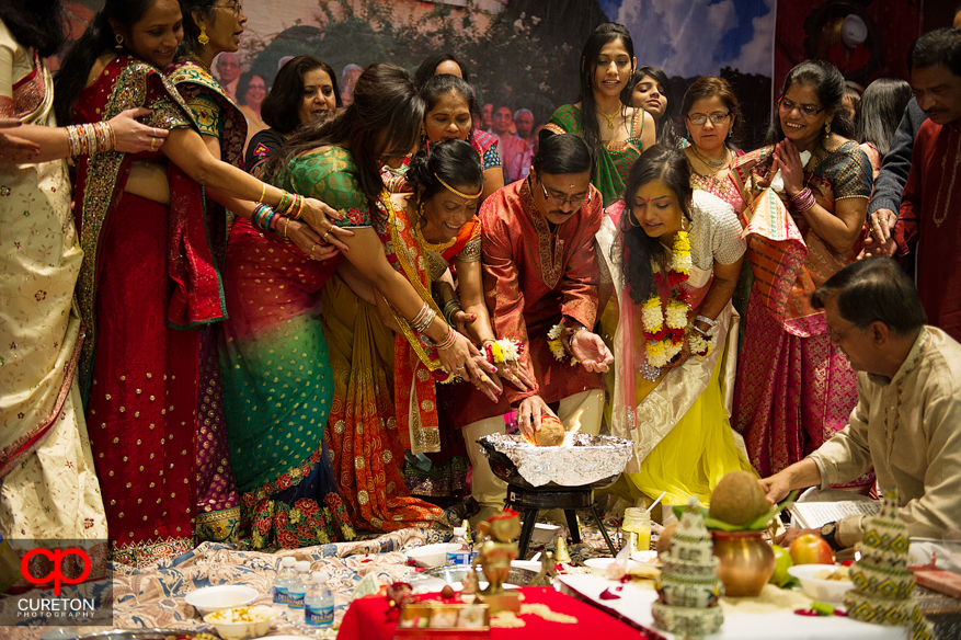 An Indian bride and her family place items in the fire during her vishi ceremony in Greenville,SC.