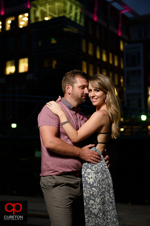 Engaged couple dancing at dusk in downtown Greenville during an engagement session.