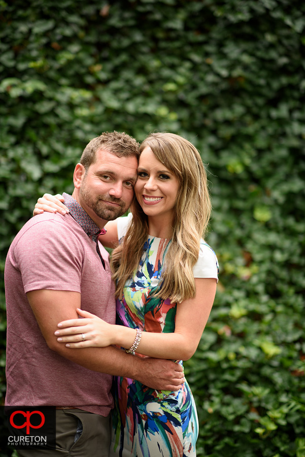 Engaged couple near a wall of ivy.