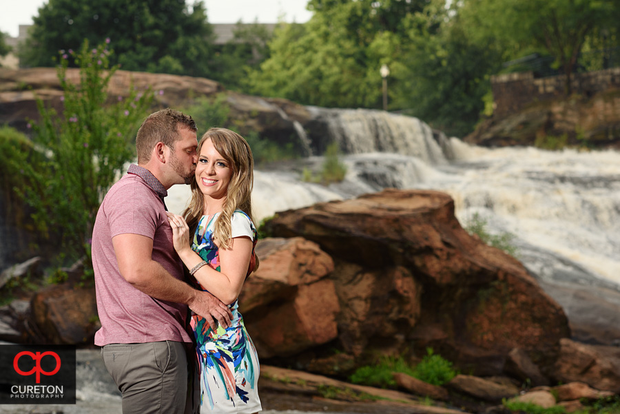 Engaged couple kissing at the waterfall.