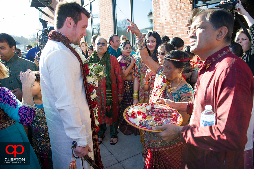 Bride;s mother greets the groom at the door during traditional Indian wedding.