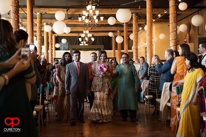 The bride is led down the aisle by her uncles.